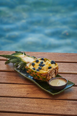 Freshly Cut Pineapple Filled with Juicy Yellow Fruit and Blueberries, Served on a Natural Wooden...
