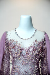 A detailed close-up of a lavender evening gown with pearl and crystal beadwork, showcasing delicate...