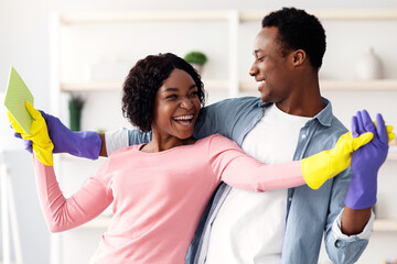 House-keeping, house cleaning concept. Cheerful african american couple young man and woman dancing...