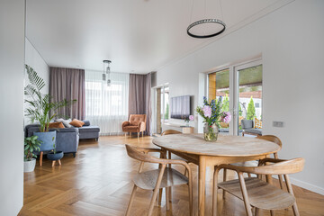 Bright and modern living space with wooden dining table and stylish lounge area in a cozy home