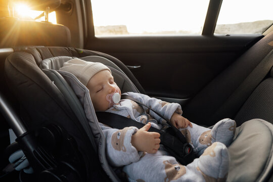 Baby sleeping in an infant car seat, safety travelling by car with little child. Little baby fastened with seat belt in safety car seat. Road trip lifestyle child care transportation rear-facing.