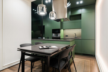 Modern kitchen design in an urban apartment featuring green cabinetry and a sleek table setup