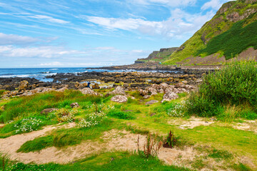 Tourists walk the Giant's Causeway along the coast of Causeway Head at the Atlantic Ocean, seen from the oceanfront trail at County Antrim on the north coast of Northern Ireland. © Kirk Fisher