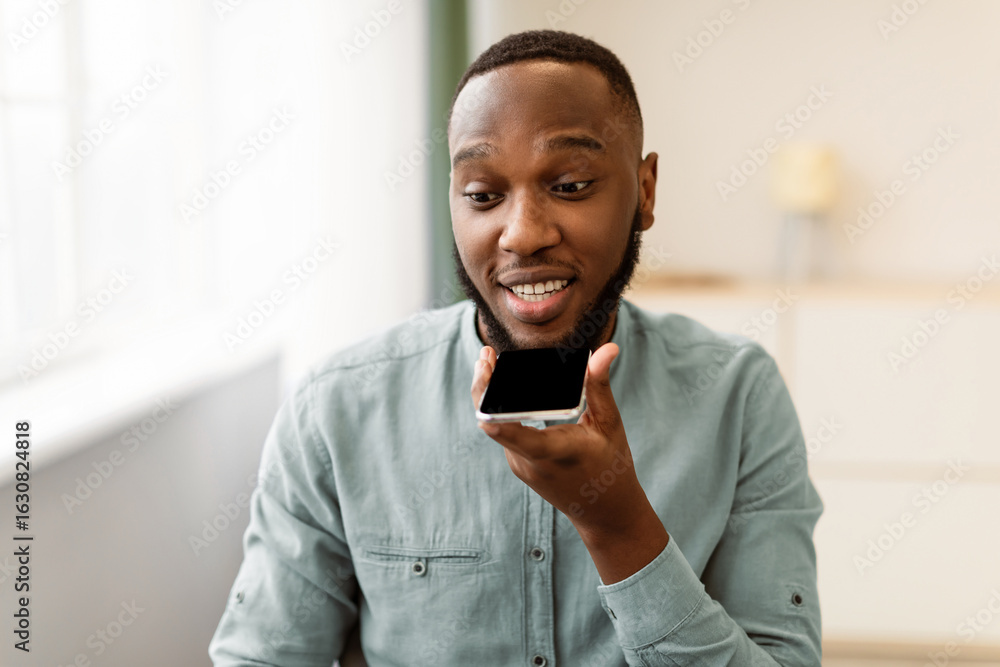 Aufkleber black business guy using cellphone with voice assistant app or chatting via loudspeaker mode sitting