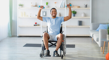 Rehab exercises for with disability people. Black guy in wheelchair working out with dumbbells at home, full length. Cheerful young man training with weights indoors