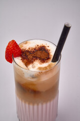 Creamy Strawberry Beverage with Frosted Ice and Whipped Topping in a Tall Glass Featuring a Striped Straw and Garnished with a Fresh Red Berry.