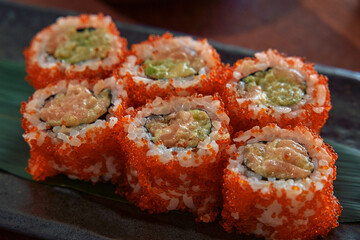 A Close-Up Look at Colorful Sushi Rolls Garnished with Vibrant Fish Roe and Creamy Fillings, Set on a Dark Plate for an Elegant Presentation