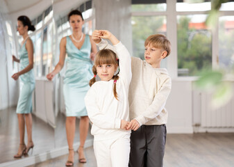 Boy with girl dressed in sport wear train to dance waltz during classes. Children rehearse...