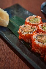 Deliciously Crafted Sushi Rolls with Vibrant Orange Roe, Accompanied by Wasabi and Soy Sauce on a Rustic Plate