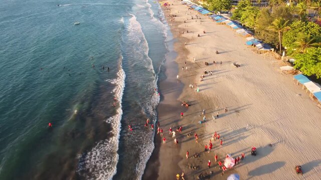 Aerial 4K drone footage of Anyer coastline at sunset. Left frame shows crashing waves, right side captures land contours. Strong wind and surf add dramatic motion.
