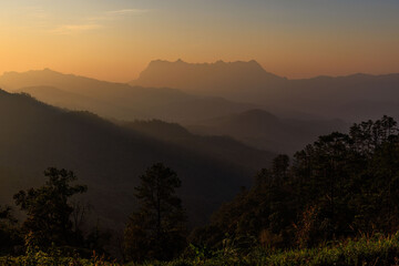 The sky is a beautiful orange color, and the mountains are covered in trees, Chiang Dao, Thailand