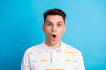 Surprised young man in casual polo shirt with stylish hairstyle starring at the camera against a...