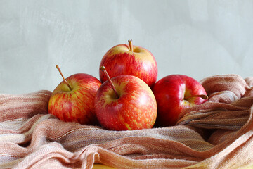Red apples on the rustic fabric with a gray background.