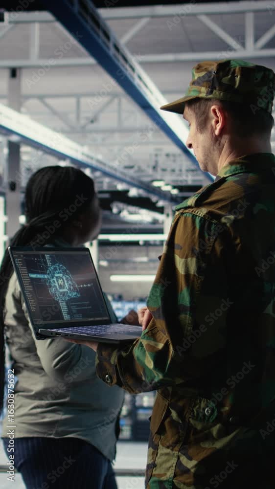 Poster vertical video soldier in engineering role uses ai application on laptop to manage server hub system