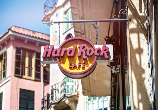Palma, Spain - Jul 15, 2025: Classic Hard Rock Cafe sign hangs above a sunny street in Palma, with Mediterranean-style shutters and colorful facades in the background.