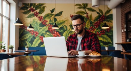 Man working on laptop in cafe with coffee and croissant lifestyle digital nomad freelance job remote work space
