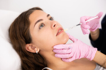 Close-up view of young woman's face undergoing mesotherapy procedure by injection in aesthetic...