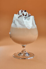 Delicious Dessert Drink with Creamy Topping and Chocolate Drizzle Served in Elegant Glass Against a Warm Background