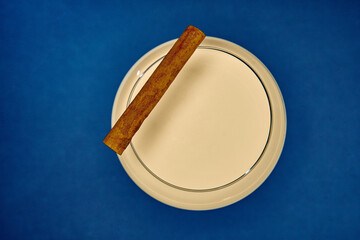 A Close-Up View of a Smooth, Creamy Liquid with a Cinnamon Stick Resting on the Rim, Set Against a...