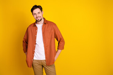 Handsome stylish man in orange shirt on vibrant yellow background showcasing trendy casual...