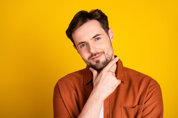 Portrait of a handsome young man with an orange shirt making thoughtful gestures against a vibrant...
