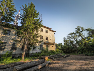 Abandoned hotel stands in a forest clearing in Serbia. Fallen logs surround the neglected concrete...