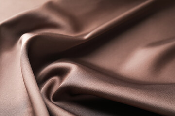 Crumpled light brown silk fabric as background, closeup