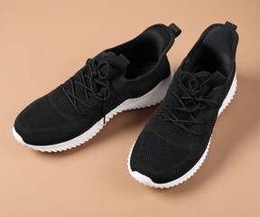 Pair of black sneakers on beige background