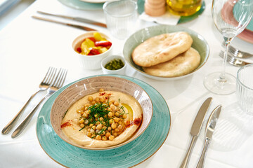 A Vibrant Platter of Hummus Garnished with Chickpeas and Fresh Herbs Accompanied by Warm Pita Bread...