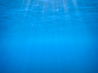 Ocean blue underwater with sunrays, Underwater Sea Deep Water Abstract Sunshine, sea wave , clean waters in summer time, Natural underwater seascape, sand on ocean floor and water surface with sunligh