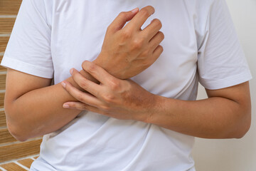 Person holding painful wrist, showing signs of sprain or inflammation. Neutral background suits...