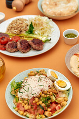 Deliciously Prepared Middle Eastern Cuisine Featuring Chickpeas, Fresh Vegetables, Grilled Meats, and Flavorful Accompaniments on a Vibrant Table Setting