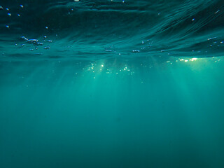 Obraz premium The sun shines through water, casting mottled light and shadow, intertwined with countless bubbles underwater, like a dance of light. Various aquatic, fish swimming in water in Mediterranean sea.