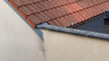 Architectural detail showing the junction of a tiled pitched roof and a bitumen flat roof on a residential house