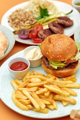 Delicious Combination of Classic Burger with Fresh Vegetables, Crispy Fries, and Tangy Dipping Sauces in an Appetizing Culinary Presentation
