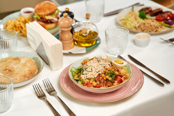 A Plentiful Table Displaying Various Delicious Dishes Including Salads, Burgers, and Sides, Perfect for a Gathered Meal Experience with Friends and Family