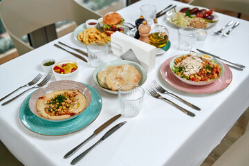 A beautifully arranged dining table featuring a variety of delectable dishes including salads, appetizers, and main courses in an elegant setting.