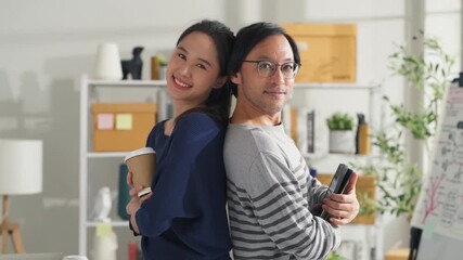 business portrait smiling asian businessman and woman partner standing fun happiness positive goodvibes confident look at cemra in modern interior home studio workshop playful businesspeople