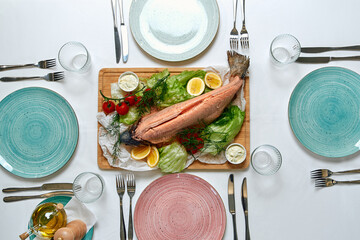 A beautifully arranged table featuring a fresh fish centerpiece garnished with vegetables and...