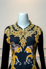 A close-up view of an elegant black wedding gown decorated with golden embroidery and traditional...