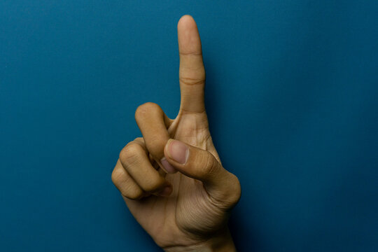Hand showing the number one against a blue backdrop