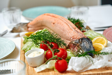 Freshly Prepared Whole Fish on a Wooden Platter Accompanied by Garnishes of Lettuce, Cherry...