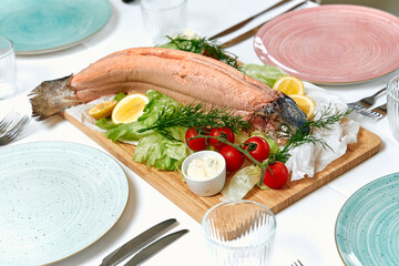 A beautifully arranged seafood platter featuring a whole salmon garnished with lettuce, tomatoes,...