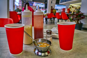 Сups with sauces and condiments on table in Pollo Listo fast food restaurant, showcasing vibrant...