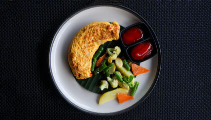 Golden fluffy omelette freshly cooked, filled with fresh ingredients, and served with vegetables and condiments. Culinary blogs, recipe illustrations, and food styling projects. Flat lay, top view.