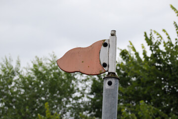 A weathered, blank, flag-shaped metal sign on a pole, a rustic template for direction or copy space