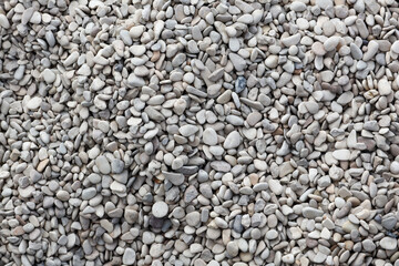 A top down texture background of smooth, grey and white pebbles or stones