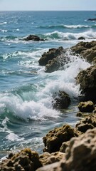 Waves crashing against rocky shoreline under clear skies