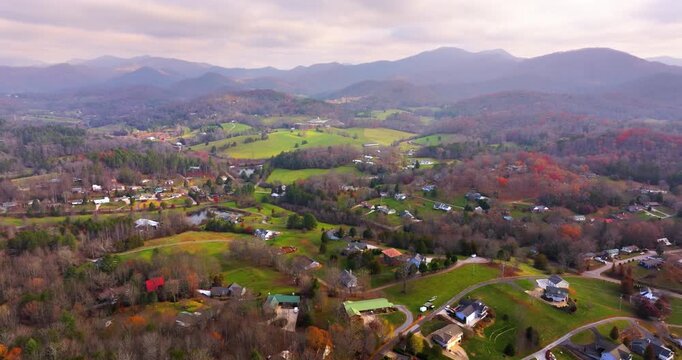 Rural houses between golden woodlands of North Carolina in fall season. Appalachian mountains with dense forest canopies