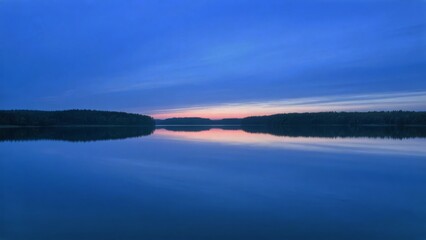 Fototapeta premium Calm Lake at Dusk with Reflective Water and Silhouetted Hills